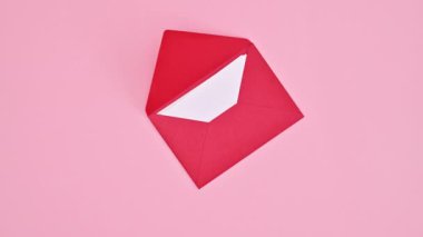 Valentine's day greeting card with copy space paper, envelope and hearts on pastel pink background. Stop motion. Flat lay
