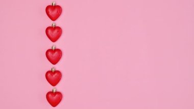 Valentine's day hearts passing on pastel pink background. Copy space flat lay. Stop motion