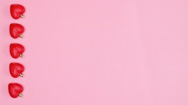 Valentine's day hearts rotate on left side of pastel pink background. Copy space flat lay. Stop motion
