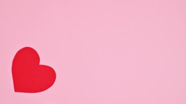 Valentine's day beating heart on pastel pink background with copy space. Stop motion flat lay