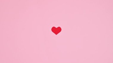 Valentine's day beating heart on pastel pink background. Stop motion flat lay
