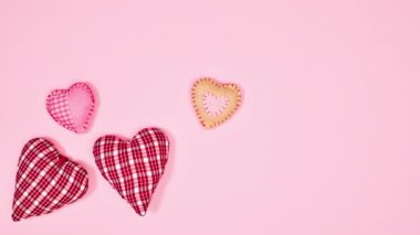 Pleated hearts appear on left side of pastel pink background. Copy space flat lay. Stop motion