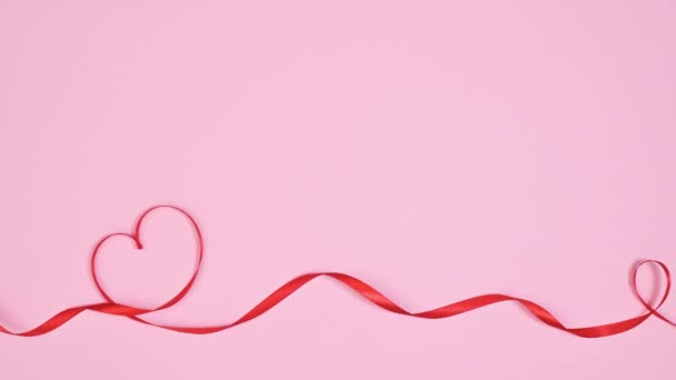 ロマンチックなリボンはパステルピンクの背景にハートの形を作ります スペースフラットレイをコピーします 動くな — ストック動画
