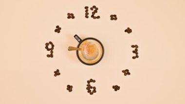 Kahve çekirdekleri ile kahve saati ve kaşığı döndürür. Hareketi durdur. Yaratıcı bir kavram. Düz yatıyordu