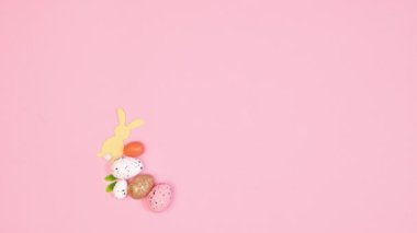 Creative Easter round frame with copy space made with eggs and Easter decorations and spring flowers on pastel pink background. Stop motion flat lay