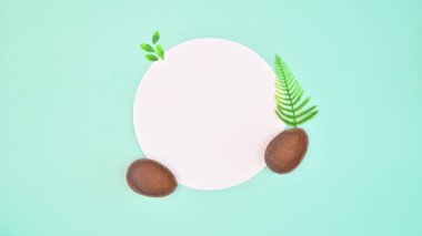 Copy space white paper surrounded with chocolate eggs and Spring holidays decorations on pastel blue background. Flat lay. Stop motion concept