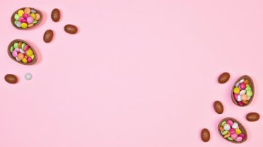 Easter arrangement with chocolate eggs appear on left and right side on pastel pink background with copy space. Flat lay. Stop motion