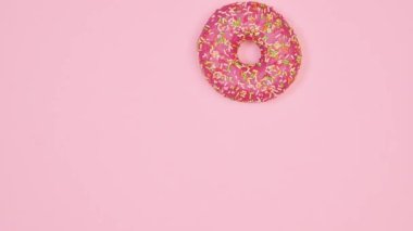 Crazy moving donut with strawberry glaze on pastel pink background. food concept Flat lay. Stop motion