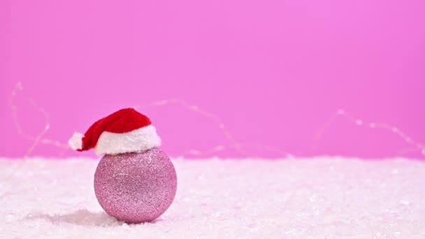 ピンクのクリスマス魔法 停止動きのライトが付いているピンクおよび雪の背景のサンタの帽子が付いている輝くピンクのクリスマスの装飾 — ストック動画