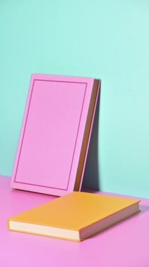 Pastel arka planda ortaya çıkan Sarı ve Pembe Kitapların Dikey Duruş Hareketi