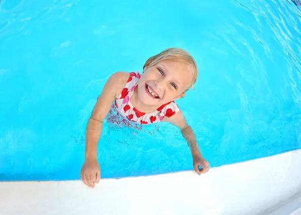 夏天的一天 一个快乐的小女孩在游泳池边的水里游泳时 对着摄像机笑着 — 图库照片