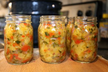 Bir grup taze konserve Pineapple Domates Pepper Salsa 'sı mutfaktaki masada oturuyor..