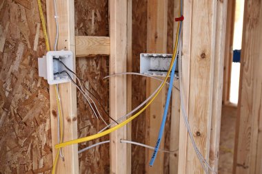 Prizler ve anahtarlar için elektrik tesisatındaki pürüzler yeni bir inşaat evinin çerçevesinde çiviler arasında görünüyor..