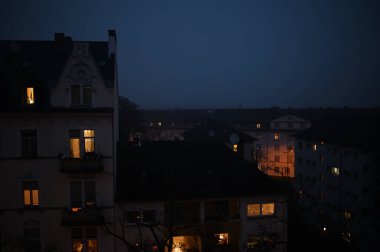 Wiesbaden (Almanya) şehrinde sisli bir akşam. Sönük sokak lambaları ve apartman pencerelerinden gelen sıcak ışık hoş ve gizemli bir atmosfer yaratarak sisli bir sonbahar gecesinin cazibesini kentsel bir ortamda mükemmel bir şekilde yakalıyor..