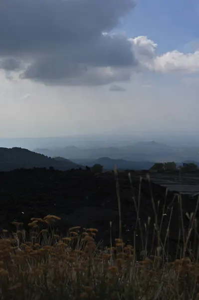 Etna Dağı 'ndaki bir volkanik sırtın silueti. Sicilya, Etna Dağı 'ndaki volkanik bir sırtın dramatik bir silueti. Bulutlu gökyüzünde tek başına görünen bir figür.. 