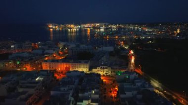Birzebbuga şehrinin, limanın, teknelerin, marinanın gece hava aracı görüntüsü. Malta adası