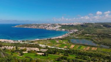 Yeşil tepelerin, denizin ve Malta adasındaki Mellieha sahillerinin insansız hava aracı görüntüsü.