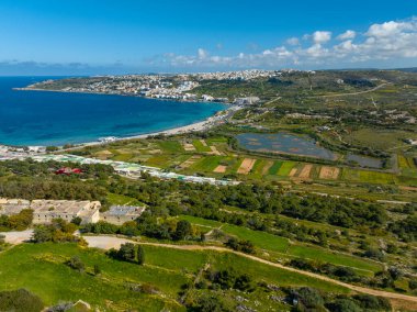 Yeşil tepelerin, denizin ve Malta adasındaki Mellieha sahillerinin insansız hava aracı görüntüsü.