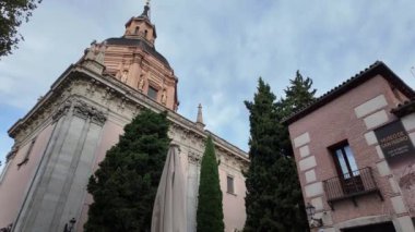 Şatafatlı bir Madrid katedralinin çarpıcı dış görünüşü, gür ağaçlarla güzelce çerçevelenmiş, hem dini mimarinin hem de çevreleyen doğal güzelliğin zarafetini sergiliyor..