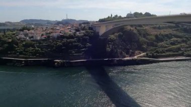 Portekiz 'in turistik bölgesinde sakin bir nehrin üzerinde uzanan beyaz bir köprünün manzarası. Aşağıda bir tekne sorunsuzca geçiyor. Bu sahneler mimari zarafetle denizcilik etkinliğinin coşkulu ruhunu birleştirir..