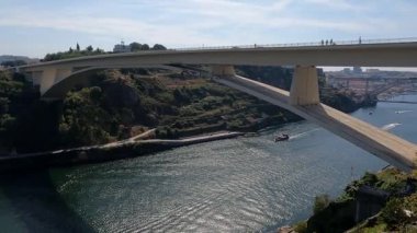 Portekiz 'in hareketli bir turistik bölgesinde sakin bir nehri kapsayan çarpıcı beyaz bir köprünün geniş açılı görüntüsü. Bu sahneler Portekiz şehir manzaralarının cazibesini yansıtıyor..