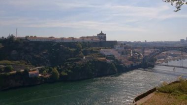 Porto, Portekiz 'in çatı manzarası, arka planda ikonik Dom Lus I Bridge ve şehrin zengin mimari manzarasına tarihi bir manastır. Videoda, dini mirasın ve modern kentsel yaşamın karışımı sergileniyor..