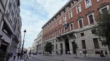İnsanlar İspanya 'da görkemli bir klasik tuğla binanın önünden geçerken modern hayatın ve tarihsel cazibenin harmanını yakalamak İspanyol mimarisinin güzelliğini gözler önüne seriyor.. 
