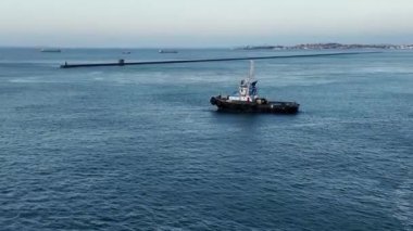 Şafak vakti huzurlu bir okyanusun cam yüzeyinde süzülen küçük bir teknenin huzurlu görüntüsü.. 