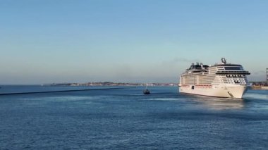 Uçsuz bucaksız ufuk boyunca okyanusta seyreden bir yolcu gemisinin çarpıcı geniş açılı görüntüsü. Bu sahne modern gemi seyahatinin büyüklüğünü ve lüksünü vurgular.. 