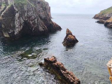 Derin Blues ve Parlak Yeşiller Bir Rocky Adası Çevresinde
