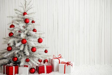 Kırmızı süsleri ve paketlenmiş hediyeleri olan şenlikli bir Noel ağacı..