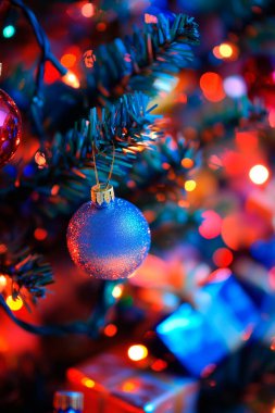 Blue Christmas ornament hangs on a tree surrounded by colorful lights. clipart