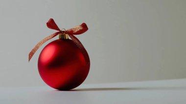 Shiny red Christmas ornament with a gold ribbon on a simple background clipart