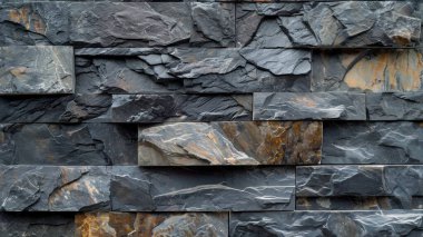 Textured dark stone wall featuring layered slate tiles in varying shades and patterns. clipart