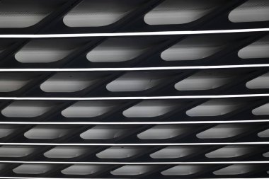 Abstract close-up of a modern ceiling with sleek, curved designs and illuminated lines. clipart