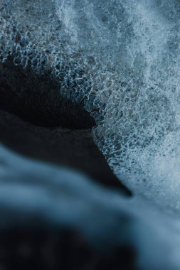 Close-up of ocean waves creating bubbles on a rocky surface. clipart