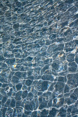 Tranquil blue water surface reflecting light patterns. clipart