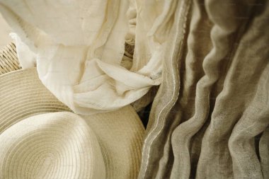 Elegant beige fabrics and a straw hat arranged artistically. clipart