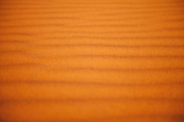 Abstract close-up of golden sand dunes with soft, wavy patterns. clipart