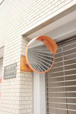 Reflective traffic mirror on a brick wall, enhancing safety for pedestrians. clipart