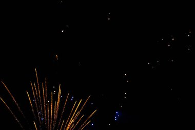 Colorful fireworks illuminating the night sky in vibrant orange and blue hues. clipart