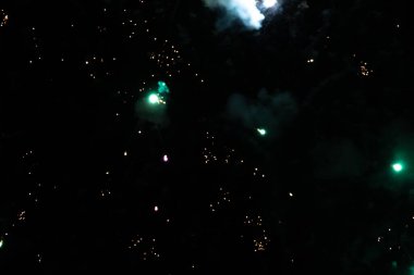 Vibrant green fireworks exploding against a dark sky. clipart