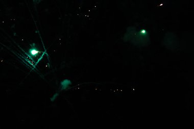 Green fireworks burst against a dark night sky. clipart