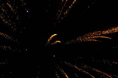 Dynamic fireworks bursting in golden sparks against a dark night sky. clipart