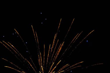 Bright golden fireworks exploding against a dark night sky. clipart