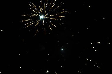 Bright fireworks burst against a dark night sky. clipart