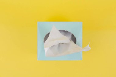 Light blue tissue box with tissue on bright yellow background. clipart