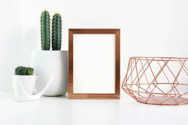 A minimalist display featuring a blank frame, cacti, and elegant decor in soft colors. clipart