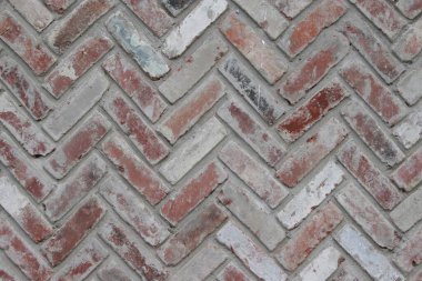 Close-up of textured herringbone-patterned brick wall in earthy tones. clipart