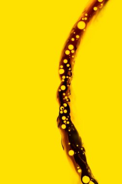 A vibrant yellow background with swirling brown liquid and bubbles. clipart